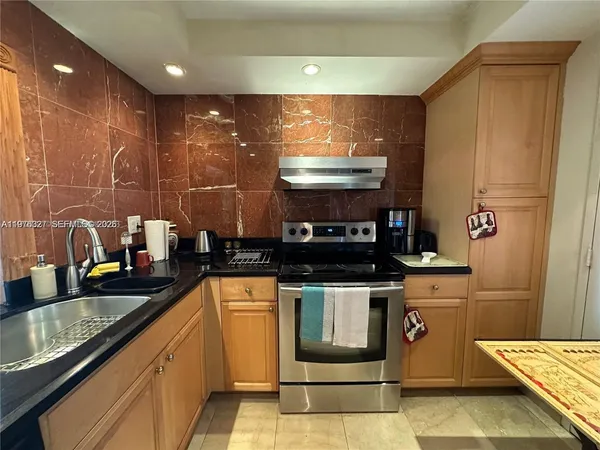 a kitchen with stainless steel appliances granite countertop a stove a sink and a microwave