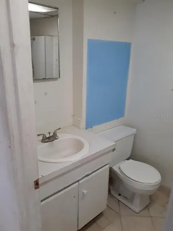 a bathroom with a toilet sink vanity and mirror