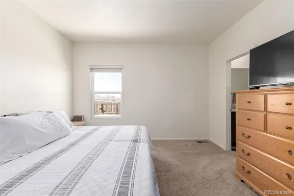 a bedroom with a bed and a flat tv screen on dresser