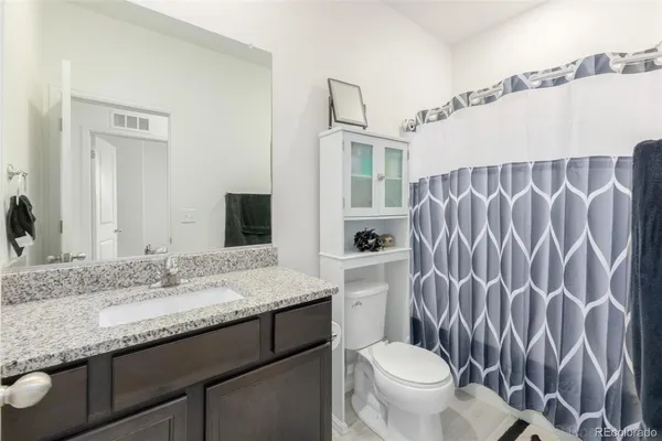 a bathroom with a granite countertop sink a toilet and a mirror