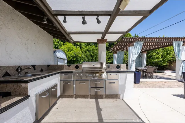 a kitchen with stainless steel appliances granite countertop a stove a sink dishwasher and white cabinets with wooden floor