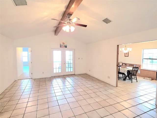 a view of empty room with window and chandelier fan