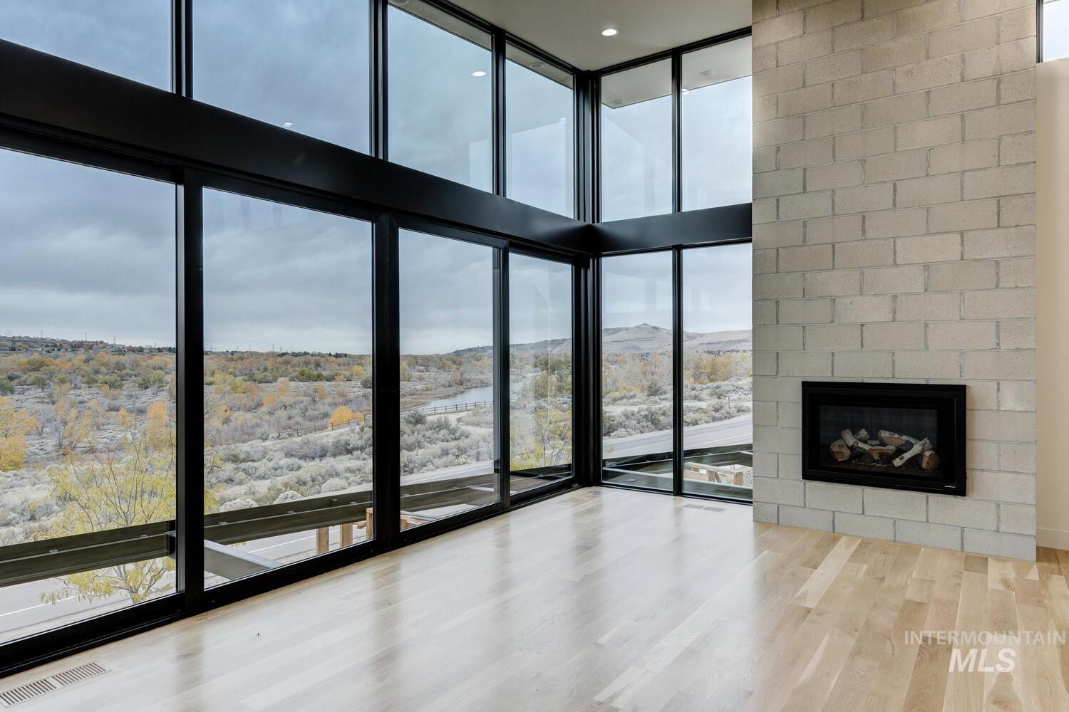 5775 South Brian Way Boise, ID 83716 - Photo 4 of 13 Unfurnished living room with light wood-style flooring, floor to ceiling windows, a large fireplace, a high ceiling, and a mountain view