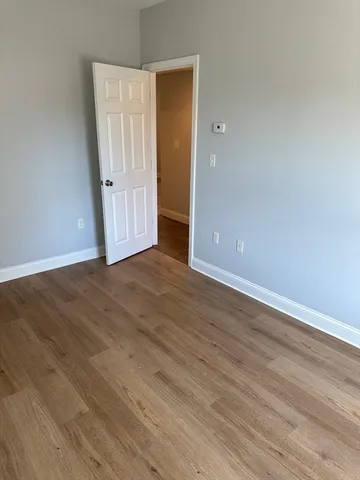 a view of an empty room with wooden floor and closet