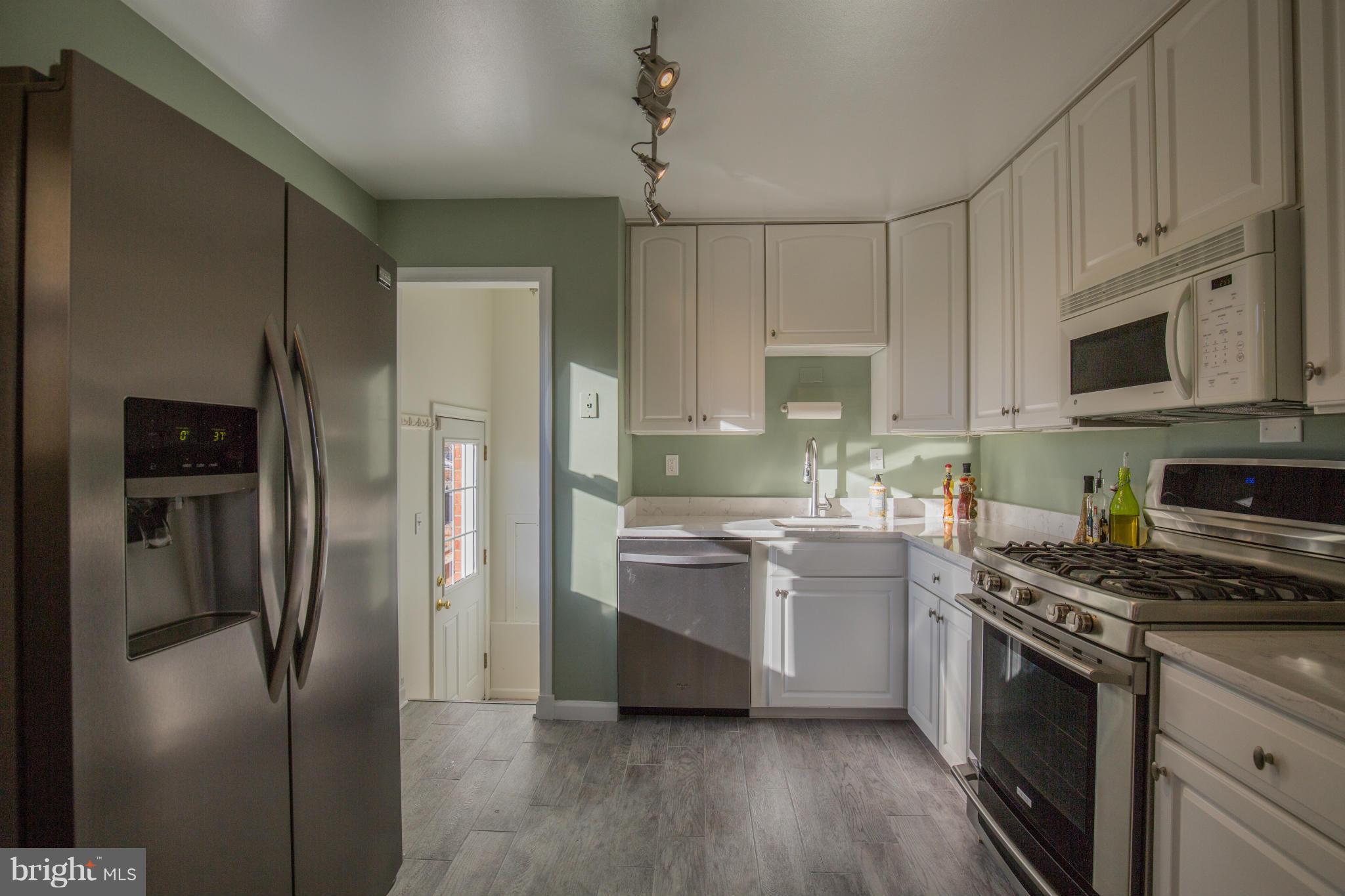 12716 Feldon Street Silver Spring, MD 20906 - Photo 8 of 30 a kitchen with stainless steel appliances granite countertop a refrigerator a stove a sink and white cabinets