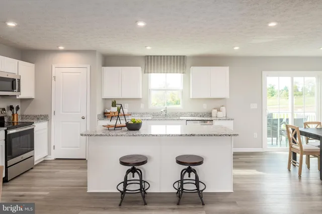 a kitchen with stainless steel appliances granite countertop a table chairs sink refrigerator and cabinets