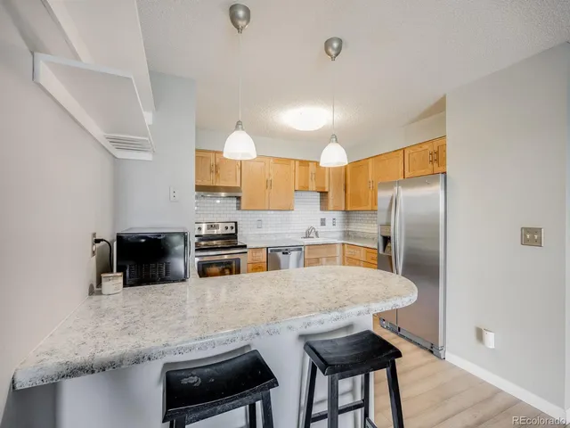 a kitchen with stainless steel appliances a refrigerator a sink a stove a dining table and chairs