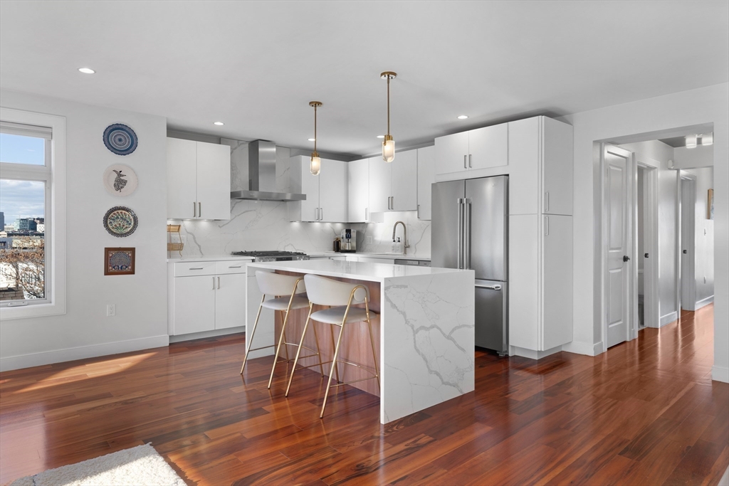 112 West 9th Street, Unit PH4 Boston, MA 02127 - Photo 2 of 34 a kitchen with stainless steel appliances a refrigerator a stove a sink dishwasher and a dining table with wooden floor