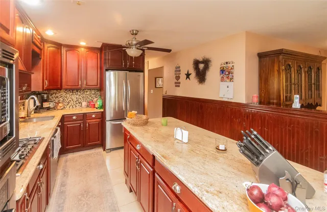 a kitchen with stainless steel appliances kitchen island granite countertop a sink stove and refrigerator