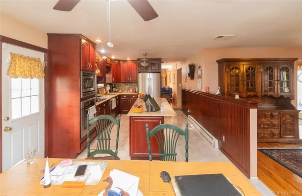 a living room with stainless steel appliances kitchen island granite countertop a table chairs and a refrigerator