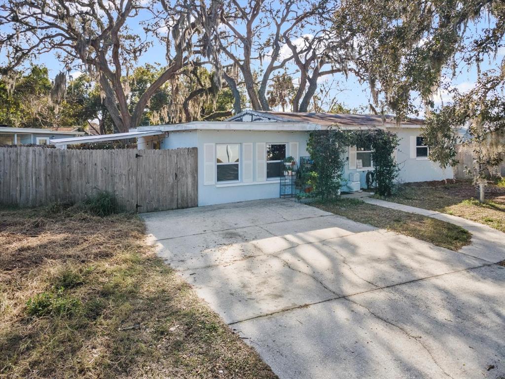 7114 Carlow Street New Port Richey, FL 34653 - Photo 5 of 65 a view of a house with a large tree and wooden fence