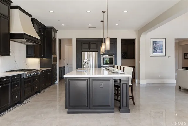 a large kitchen with a large counter top a sink stainless steel appliances and cabinets