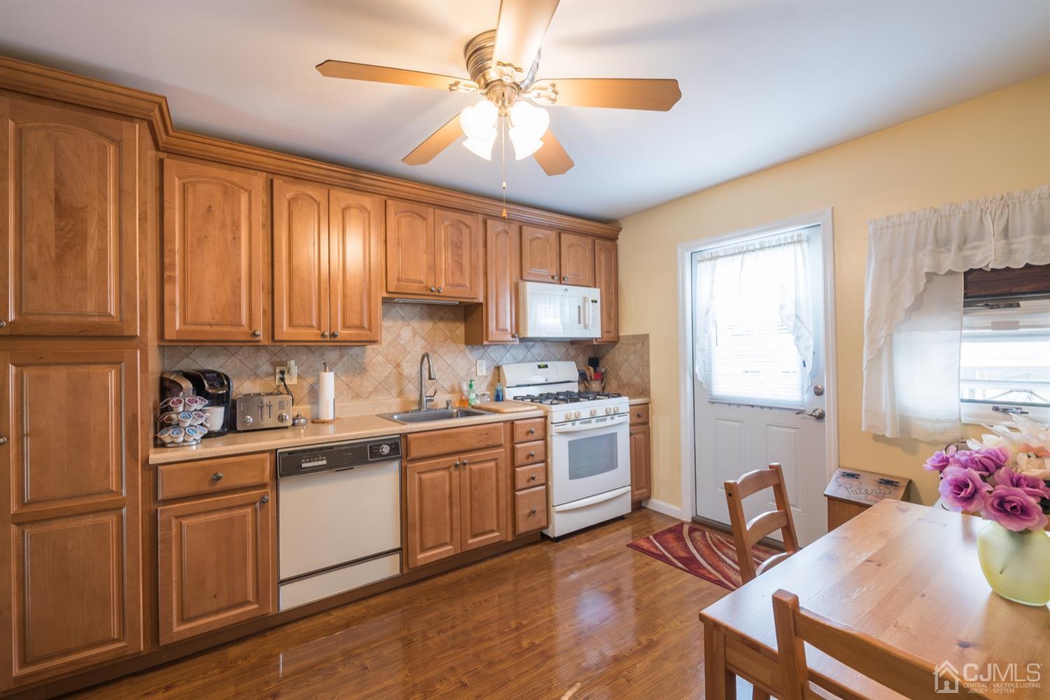 8 Wilk Road Edison, NJ 08837 - Photo 9 of 20 a kitchen with a stove a sink dishwasher a dining table and chairs with wooden floor