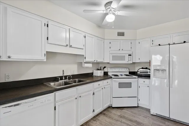 a kitchen with granite countertop white cabinets white stainless steel appliances and sink
