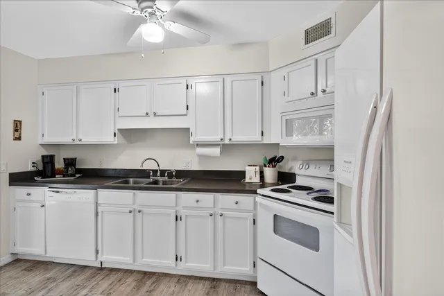 a kitchen with granite countertop white cabinets and white appliances
