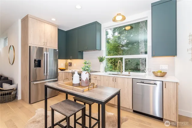 a kitchen with a refrigerator a stove a sink and a dining table with wooden floor