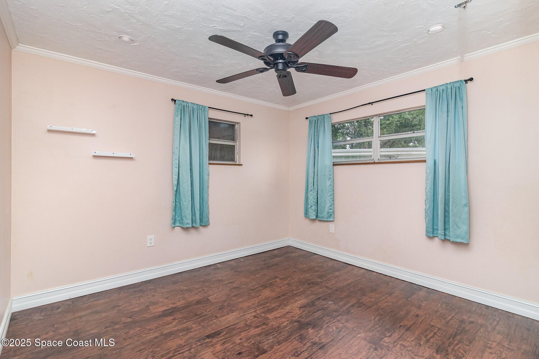 13 Scott Lane Rockledge, FL 32955 - Photo 17 of 26 an empty room with wooden floor ceiling fan and windows