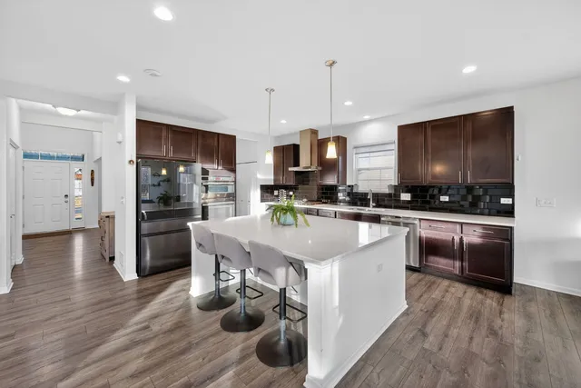 a kitchen with stainless steel appliances granite countertop a refrigerator a stove top oven a sink dishwasher and white cabinets with wooden floor