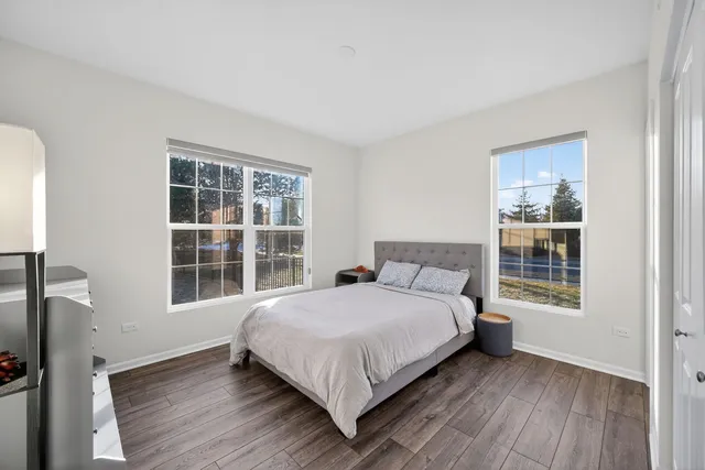 a view of a bedroom with wooden floor and windows