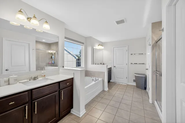 a spacious bathroom with a double vanity sink toilet mirror and bathtub