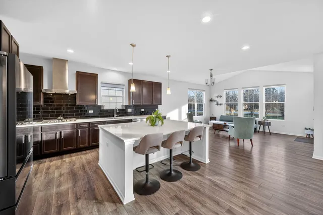 a kitchen with stainless steel appliances a dining table chairs stove and cabinets