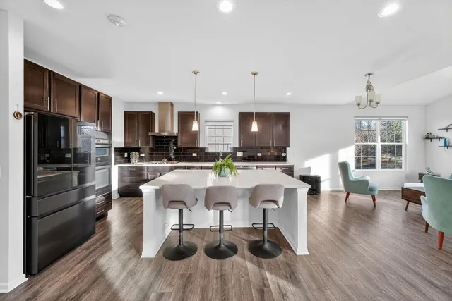 a kitchen with stainless steel appliances a dining table chairs stove refrigerator and cabinets