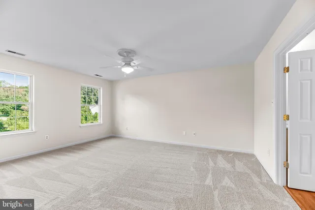 an empty room with windows and chandelier fan
