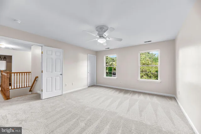 an empty room with windows and ceiling fan