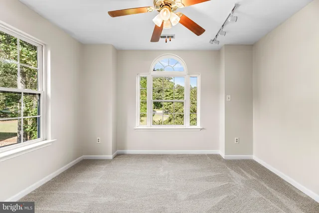 an empty room with windows and chandelier fan