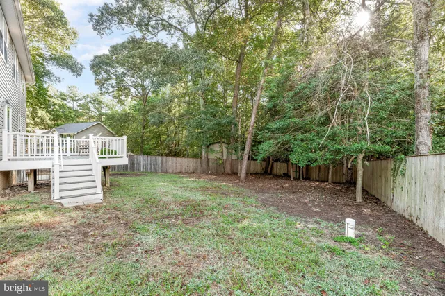 a view of a backyard with wooden fence and large trees