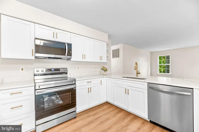 a kitchen with white cabinets appliances and a window
