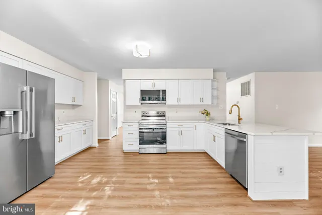 a large kitchen with cabinets wooden floor and stainless steel appliances
