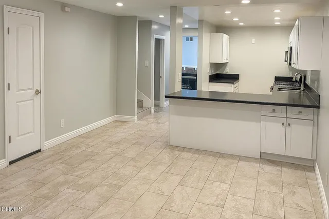 a view of a kitchen with kitchen island white cabinets and stainless steel appliances