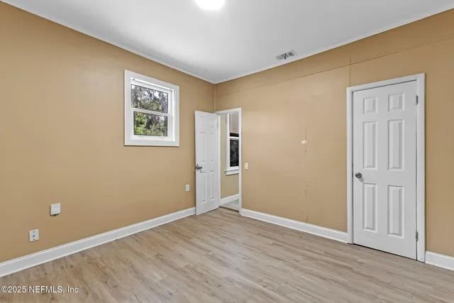 a view of an empty room with wooden floor and closet