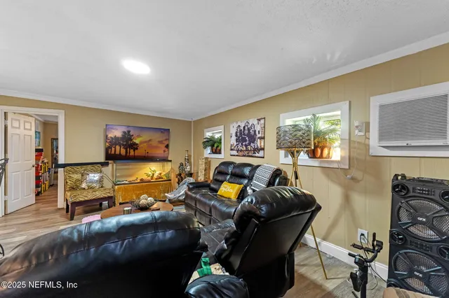 a living room with furniture and a flat screen tv with kitchen view