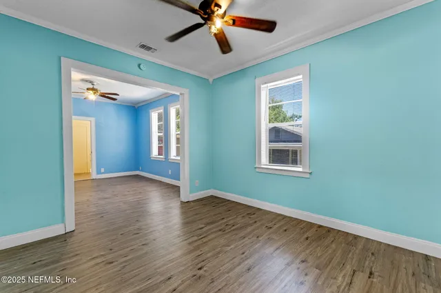 a view of an empty room with window and wooden floor
