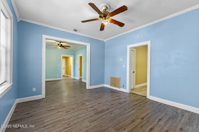 a view of an empty room with window and wooden floor