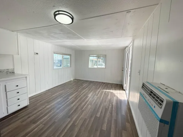 a view of an empty room with wooden floor and a window