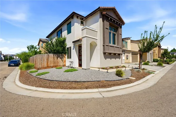 a view of a white house with a small yard and potted plants