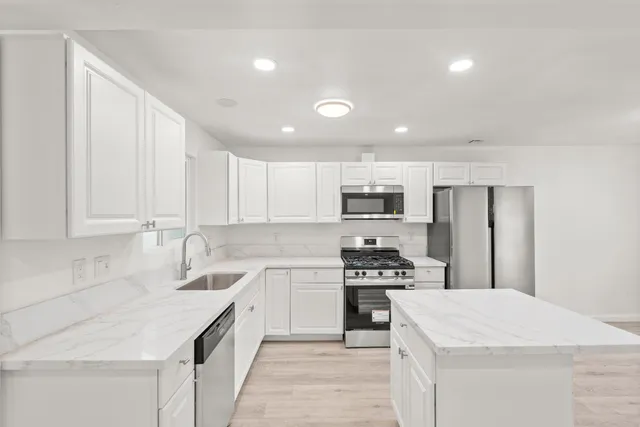 a kitchen with stainless steel appliances kitchen island granite countertop a sink stove and cabinets