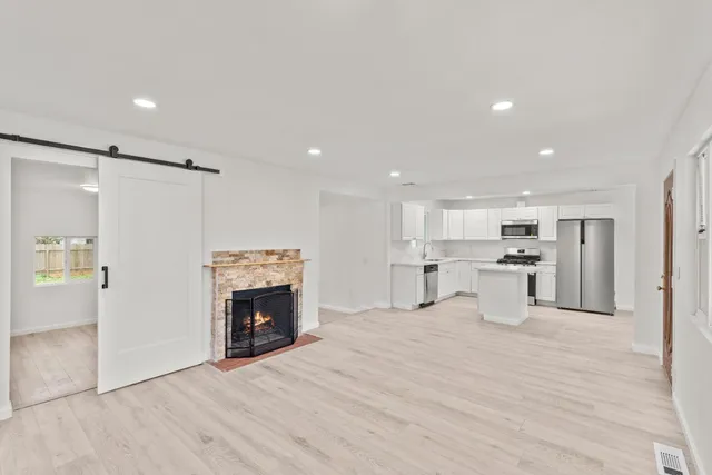 a view of empty room with kitchen and fireplace