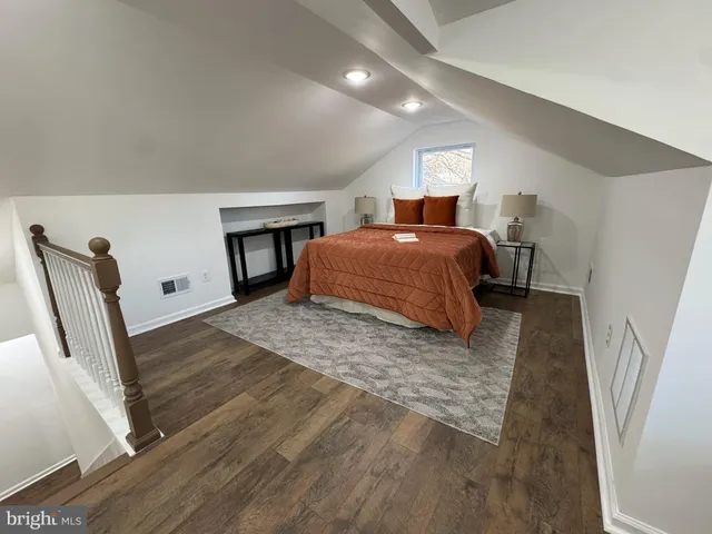 a spacious bedroom with a bed and wooden floor