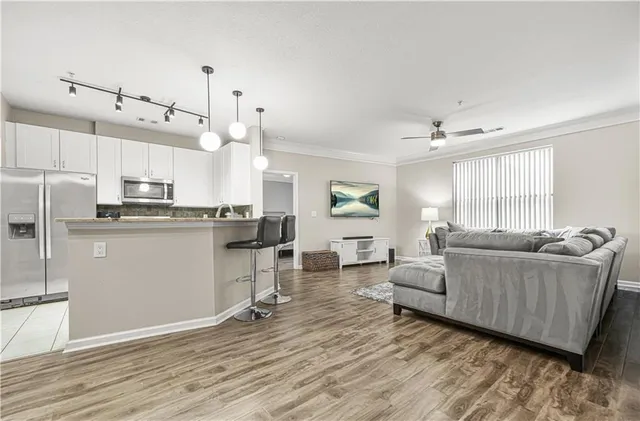 a living room with couches and kitchen view with wooden floor