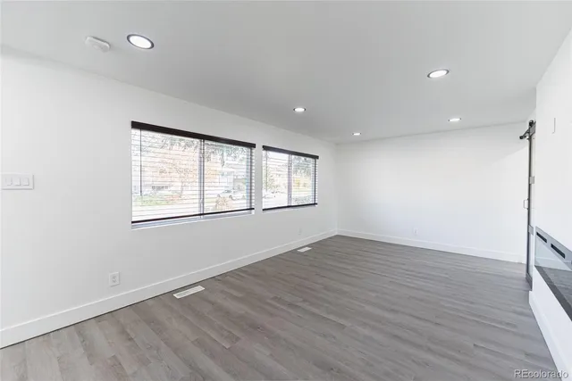 an empty room with wooden floor and windows