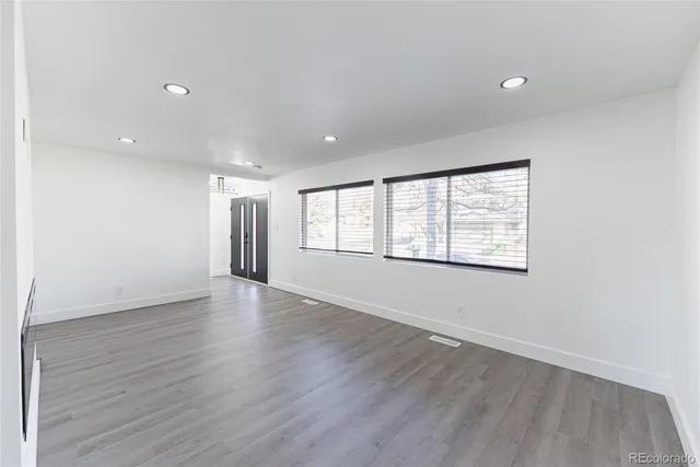 an empty room with wooden floor and windows