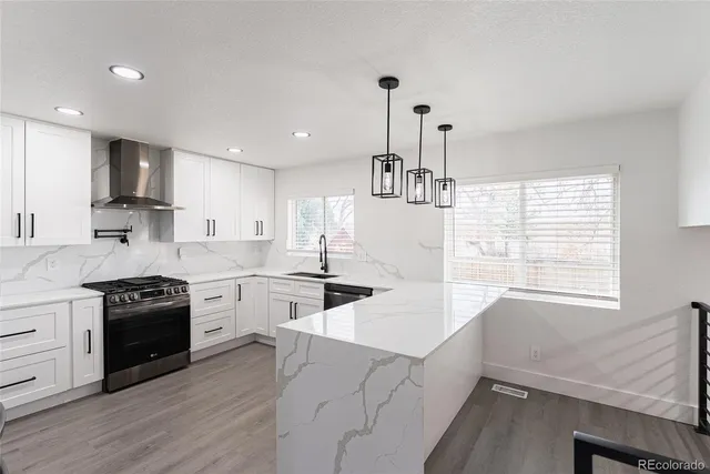 a kitchen with stove a sink and white cabinets with wooden floor
