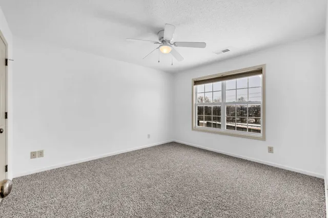 an empty room with a ceiling fan and a window