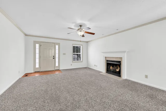 a view of an empty room with chandelier fan and fireplace