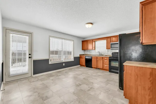 a large kitchen with stainless steel appliances granite countertop a stove sink and cabinets