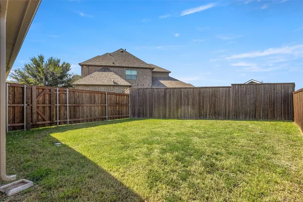 a view of backyard of house with wooden fence